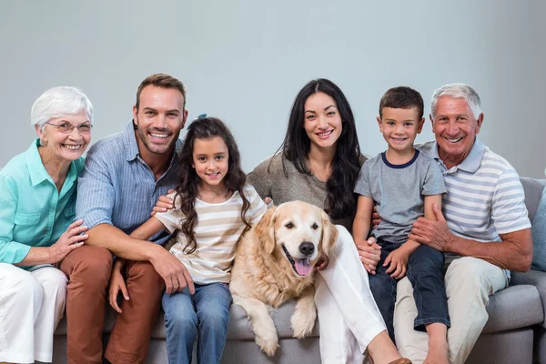 Familjen sitter på soffan med hunden — Stockfoto