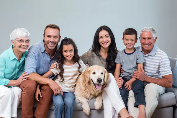 Família sentada no sofá com cão — Fotografia de Stock