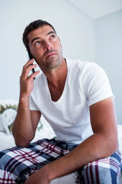 Homem sentado na cama falando ao telefone — Fotografia de Stock