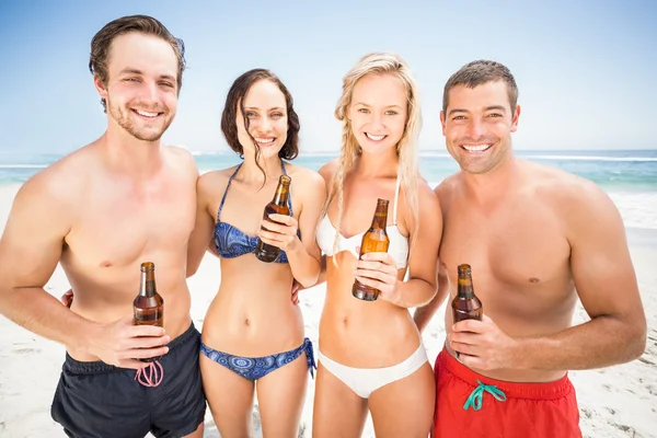 Retrato de amigos felizes em pé na praia com garrafa de cerveja — Fotografia de Stock