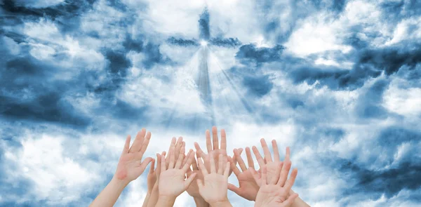 People raising hands against cross — Stock Photo, Image