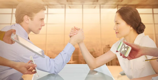 Business couple arm wrestling at desk — Stock Photo, Image