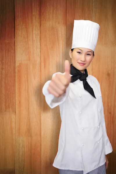 Χαμογελώντας μαγείρισσα χειρονομώ αντίχειρες επάνω στην κουζίνα — Φωτογραφία Αρχείου