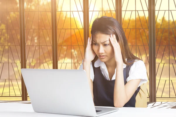 Composietbeeld van nerveuze zakenvrouw met behulp van een laptop — Stockfoto