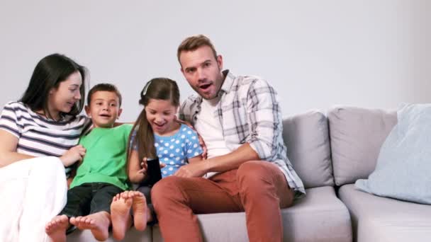 Niedliche Familie fernsehen auf der Couch — Stockvideo