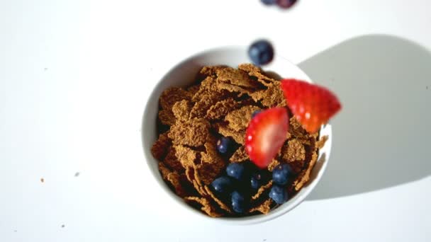 Strawberries and blueberries falling in a wheat cereals — Stock Video