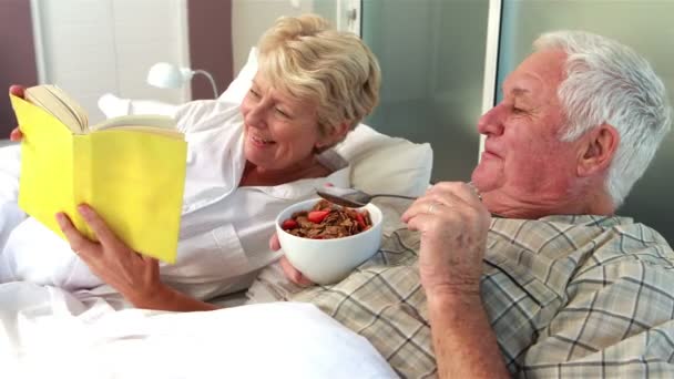 Senioren lesen Buch und essen Müsli — Stockvideo