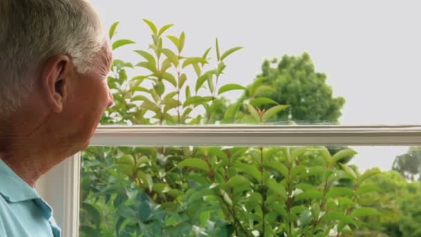 Senior mannen tittar på fönster — Stockvideo
