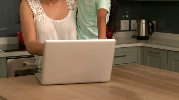 Мать и дочь используют ноутбук на кухне — стоковое видео