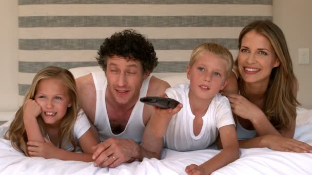 Mignonne famille regarder la télévision sur leur lit — Video