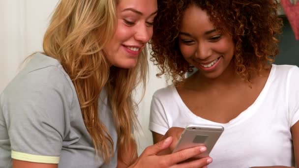 Две улыбающиеся юные подруги читают смс — стоковое видео