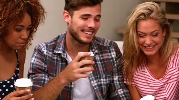 Друзья сидят на диване и болтают за чашечкой кофе — стоковое видео