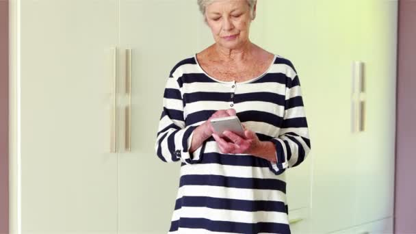 年配の女性が彼女のスマート フォンを使用して — ストック動画