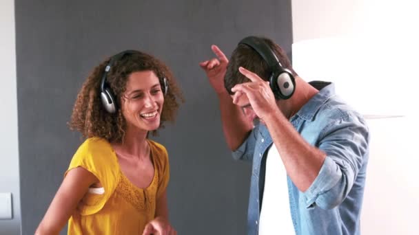 Linda pareja escuchando música con auriculares y bailando — Vídeos de Stock