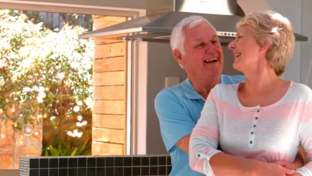 Пожилая пара обнимается на кухне — стоковое видео