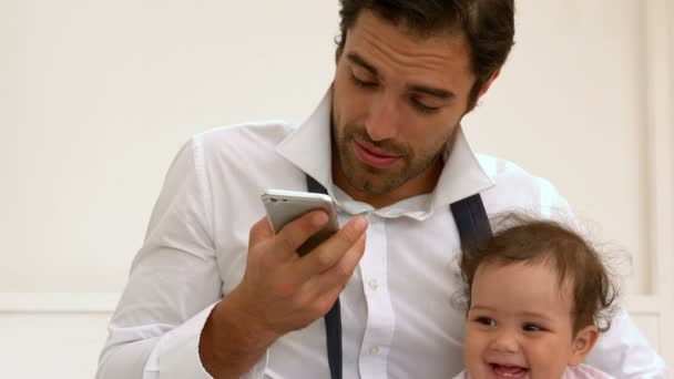 Отец с ребенком и разговаривает по телефону — стоковое видео