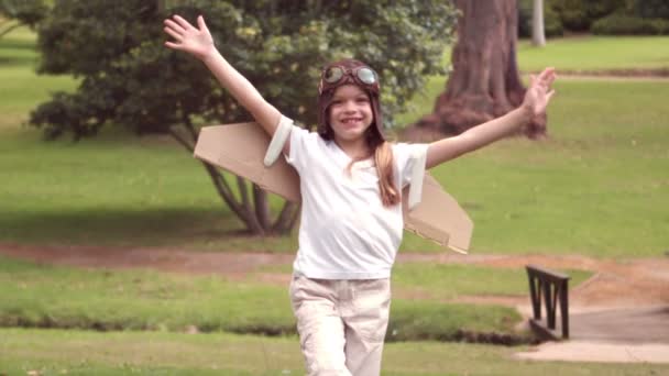 Стоїть дівчина з фальшивими крилами, прикидаючись пілотом — стокове відео