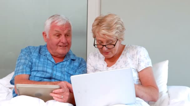 Äldre par med hjälp av Tablet PC och laptop — Stockvideo