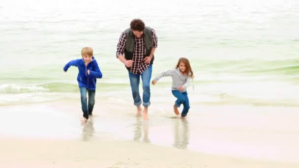 Père et enfants courant sur la plage — Video