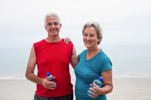 Smiling senior couple holding bottle — Stock Photo, Image