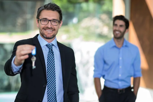 Real estate agent holding key — Stock Photo, Image