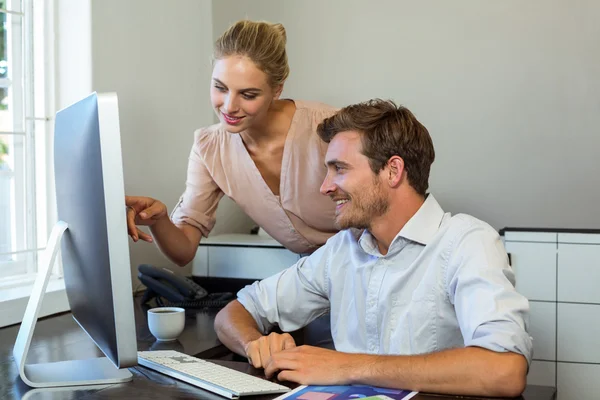 Female colleague pointing on computer — Stock Photo, Image