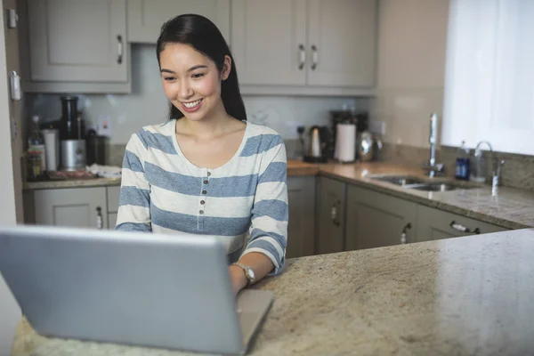 Mujer usando portátil en la cocina —  Fotos de Stock