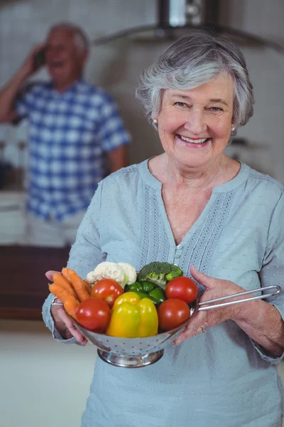 Mulher segurando escorredor com legumes — Fotografia de Stock