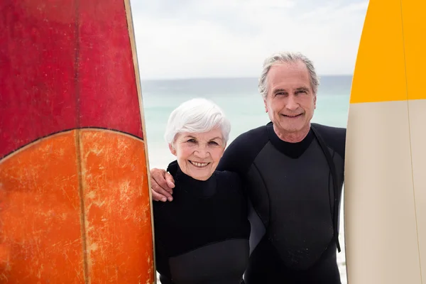 Senior paar met surfboard op strand — Stockfoto