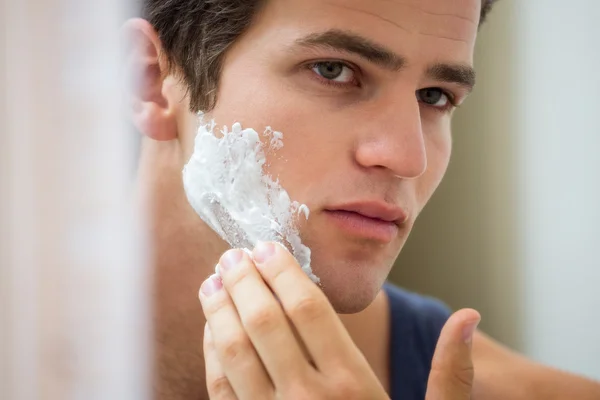 Homem aplicando espuma de barbear no rosto — Fotografia de Stock