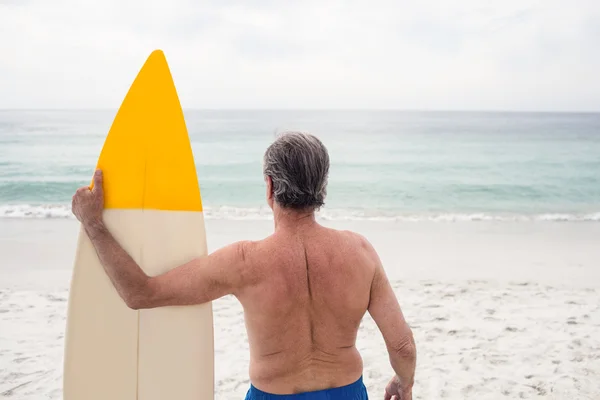 Mann steht mit Surfbrett am Strand — Stockfoto