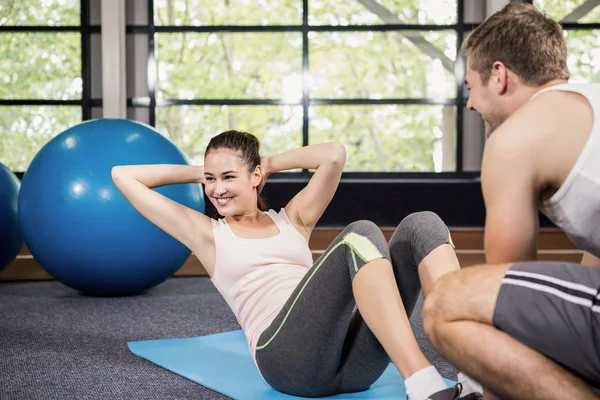 Trainer assisting woman with abdominal crunches — Stock Photo, Image