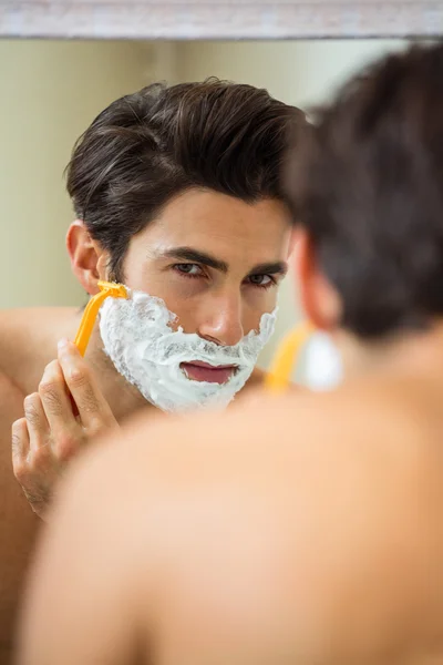 Homem que reflete no espelho ao barbear a barba — Fotografia de Stock