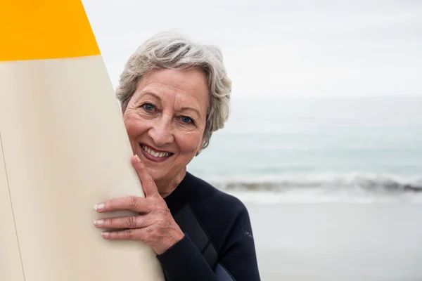 Mujer mayor en traje de neopreno sosteniendo tabla de surf — Foto de Stock