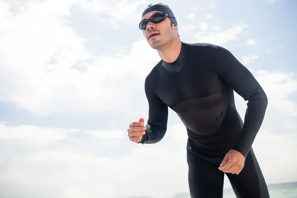 Man in wetsuit uitvoeren op strand — Stockfoto