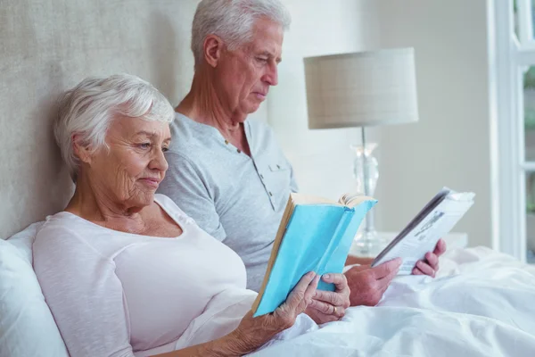 Senior couple reading books on bed — Stock Photo, Image