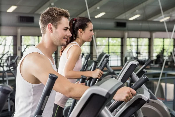 Mujer y hombre haciendo ejercicio en la máquina elíptica — Foto de Stock