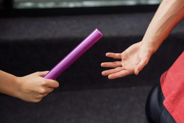 Athlete passing baton to partner — Stock Photo, Image