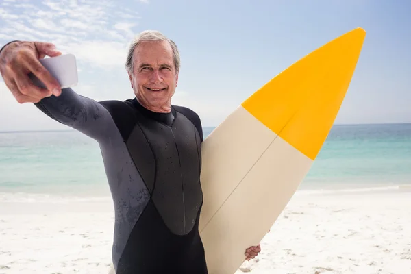 Senior man nemen selfie met surfboard — Stockfoto