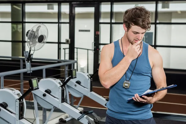 Gym trainer looking at clipboard