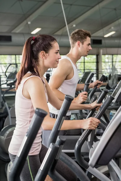 Femme et homme exerçant sur machine elliptique — Photo