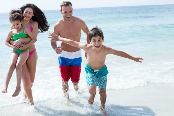 Szczęśliwa rodzina działa na plaży — Zdjęcie stockowe
