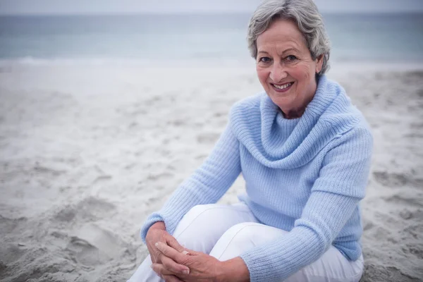 Starší žena sedí na pláži — Stock fotografie