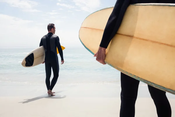 Mężczyznę idącego z deski surfingowej na plaży — Zdjęcie stockowe