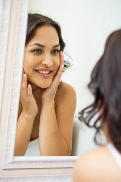 Woman looking in mirror of bathroom — Stock Photo, Image