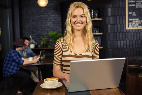 Femme buvant du café et utilisant un ordinateur portable — Photo