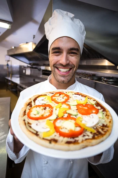 Stilig kocken presenterar pizza — Stockfoto