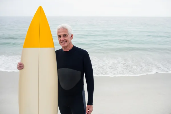 Homme en combinaison tenant une planche de surf — Photo