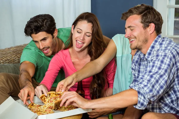 Happy vrienden stuk van pizza afhalen — Stockfoto