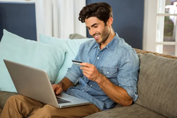 Hombre sentado en el sofá y compras en línea — Foto de Stock